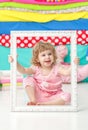 Little cute girl in a pink suit sitting on the floor and smiling over wooden white frame. Royalty Free Stock Photo