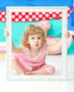 Little cute girl in a pink suit sitting on the floor and smiling over wooden white frame. Royalty Free Stock Photo