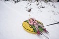 Little cute girl in pink warm outwear having fun rides inflatable snow tube in snowy white cold winter outdoors. Family sport Royalty Free Stock Photo