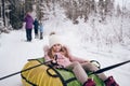 Little cute girl in pink warm outwear having fun rides inflatable snow tube in snowy white cold winter outdoors. Family sport Royalty Free Stock Photo