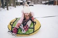 Little cute girl in pink warm outwear having fun rides inflatable snow tube in snowy white cold winter outdoors. Family sport Royalty Free Stock Photo