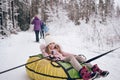 Little cute girl in pink warm outwear having fun rides inflatable snow tube in snowy white cold winter outdoors. Family sport Royalty Free Stock Photo