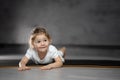 Little cute girl practicing yoga pose on grey background in dark room Royalty Free Stock Photo