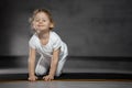 Little cute girl practicing yoga pose on grey background in dark room Royalty Free Stock Photo