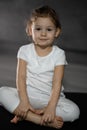 Little cute girl practicing yoga pose on grey background in dark room Royalty Free Stock Photo