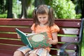 Little cute girl preschooler with book on bench