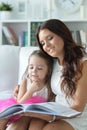 Little cute girl reading book with mother while sitting on safe Royalty Free Stock Photo