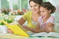 Little cute girl reading book with mother at the table at home Royalty Free Stock Photo