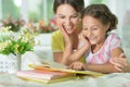 Little cute girl reading book with mother at the table at home Royalty Free Stock Photo