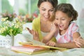 Little cute girl reading book with mother at the table at home Royalty Free Stock Photo