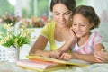 Little cute girl reading book with mother at the table at home Royalty Free Stock Photo