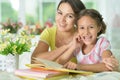 Little cute girl reading book with mother at the table at home Royalty Free Stock Photo