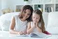 Little cute girl reading book with mother at the table Royalty Free Stock Photo