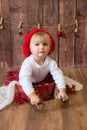 A little cute girl in a red plaid skirt and a red felt beret plays with cones and Christmas toys in a room decorated for Christmas Royalty Free Stock Photo