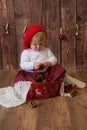 A little cute girl in a red plaid skirt and a red felt beret plays with cones and Christmas toys in a room decorated for Christmas Royalty Free Stock Photo