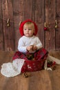 A little cute girl in a red plaid skirt and a red felt beret plays with cones and Christmas toys in a room decorated for Christmas Royalty Free Stock Photo