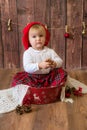 A little cute girl in a red plaid skirt and a red felt beret plays with cones and Christmas toys in a room decorated for Christmas Royalty Free Stock Photo