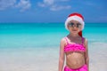 Little cute girl in red Santa hat on tropical