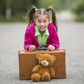 Little cute girl on the road with a suitcase