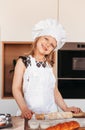 A little cute girl with a rolling pin for dough in the kitchen. The child cooks buns. Children cook food Royalty Free Stock Photo