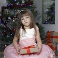 little cute girl is sad by the christmas tree. the child does not like the gift Royalty Free Stock Photo