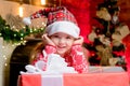 Little cute girl in Santas`s hat chherful smile. Christmas gifts. Little child having fun and playing near Christmas Royalty Free Stock Photo