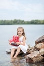 Little cute girl and scarlet sails. Girl sitting on the rocks on the seashore ocean with the ship. Happy childhood carefree game