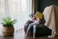 Little cute girl sitting on a bean bag with a book Royalty Free Stock Photo