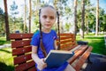 little cute girl is sitting on a bench and is reading a book Royalty Free Stock Photo