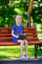 Little cute girl is sitting on a bench and is reading a book Royalty Free Stock Photo