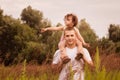 Little girl is sitting on her father`s shoulders in the summer in the park Royalty Free Stock Photo