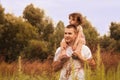 Little girl is sitting on her father`s shoulders in the summer in the park Royalty Free Stock Photo