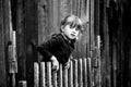 Little cute girl standing near vintage rural fence. Black and white photography.