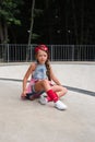 Little cute girl with sunglasses and cap sitting on a skateboard. photo of cute preteen girl with skateboard outdoors.