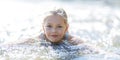 Little cute girl swims in the river, smiles. Happy childhood times in summer Royalty Free Stock Photo