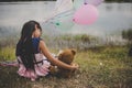 Little cute girl with teddy bear sitting on long green grass out Royalty Free Stock Photo