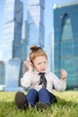 Little cute girl in tie sits on grass and talks by Royalty Free Stock Photo