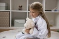 Little cute girl use stethoscope listen fluffy toy bear heartbeat