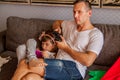 Little cute girl is using tablet, her father is playing console . Royalty Free Stock Photo