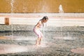 Little cute girl walking in open street fountain at hot sunny day Royalty Free Stock Photo