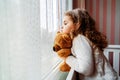 Little cute girl is watching from window to the rain with sadness get bored. Royalty Free Stock Photo