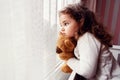 Little cute girl is watching from window to the rain with sadness get bored. Royalty Free Stock Photo