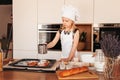 A little cute girl in a white chef`s hat prepares buns in the kitchen Royalty Free Stock Photo