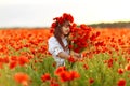 Little cute girl in white dress playing field poppy wreath with a bouquet of poppies in her hands Royalty Free Stock Photo