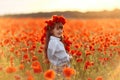 Little cute girl in white dress playing field poppy wreath with a bouquet of poppies in her hands Royalty Free Stock Photo