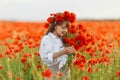 Little cute girl in white dress playing field poppy wreath with a bouquet of poppies in her hands Royalty Free Stock Photo