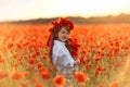 Little cute girl in white dress posing in wreath on her head with a bouquet of poppies in her hands Royalty Free Stock Photo