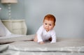 Little cute girl in white romper crawling on bed. Royalty Free Stock Photo