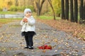 Little cute girl in white stands near red rowanberry