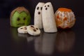 Little cute halloween style monsters and ghosts made from cut fruit and decorated on reflective black background